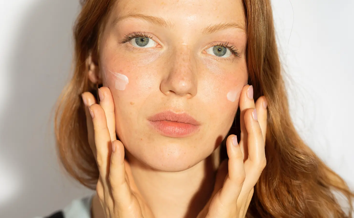 Kobieta nakładająca krem na policzki, promująca kosmetyki Yun.