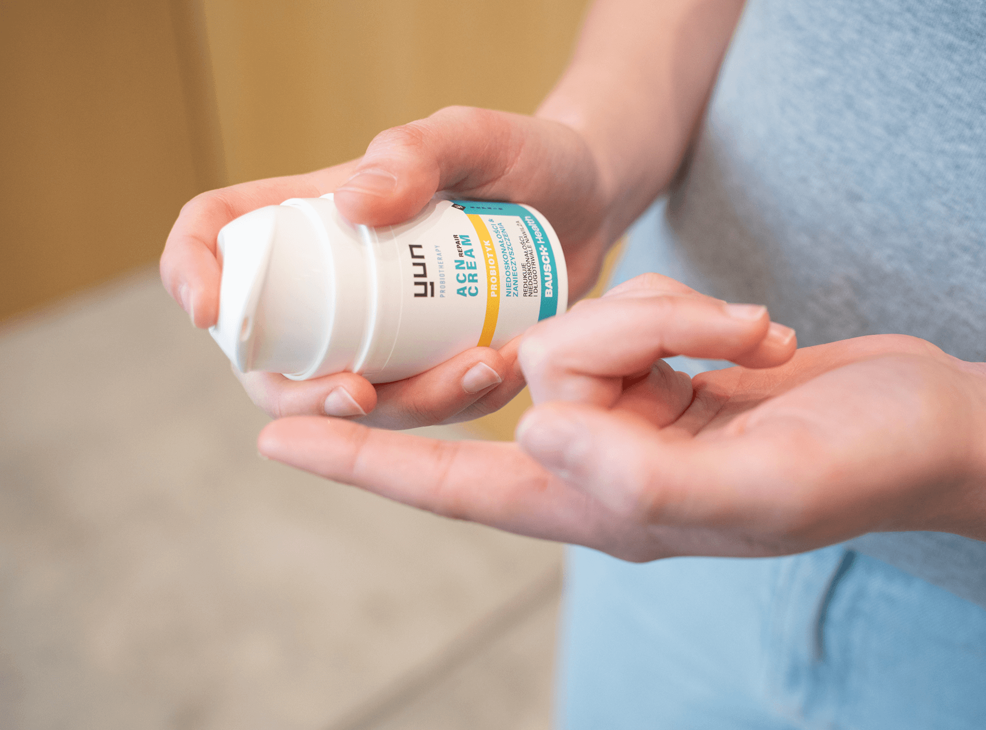 Osoba trzymająca i nakładająca na palec krem Yun ACN Repair Cream