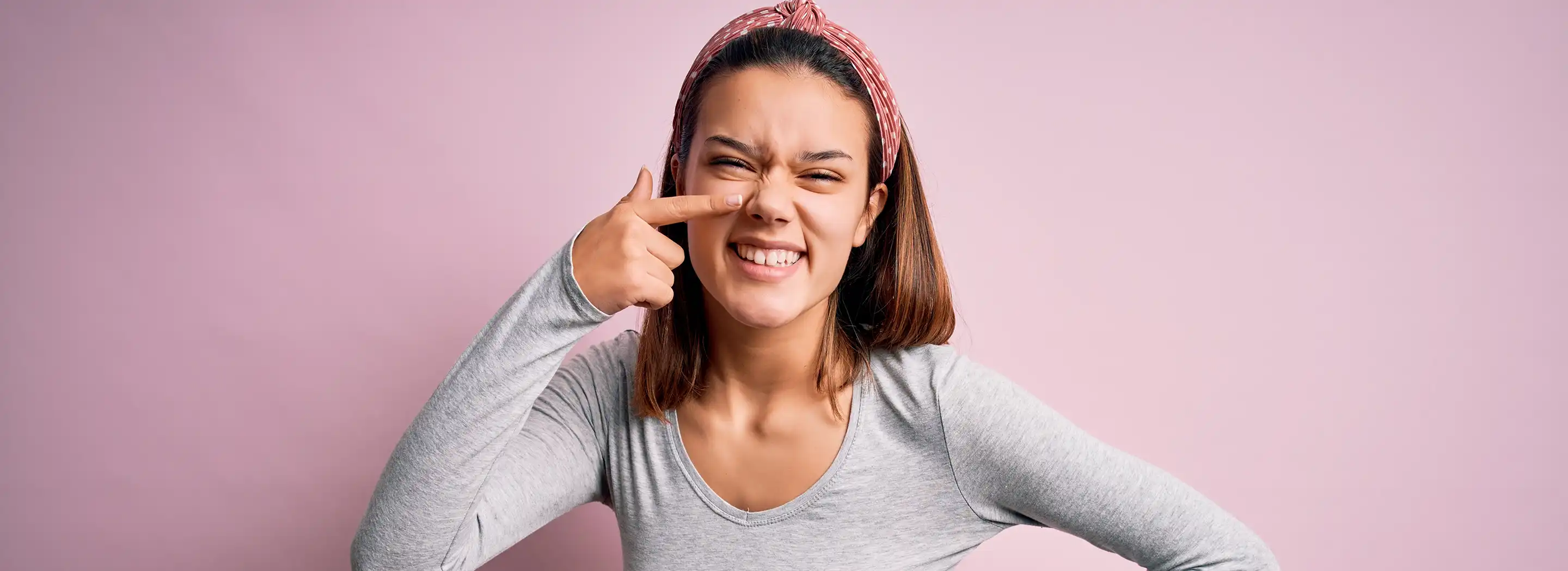 Osoba w ciąży wskazująca okolice policzka, symbolizująca bezpieczną pielęgnację cery skłonnej do trądziku w czasie ciąży.