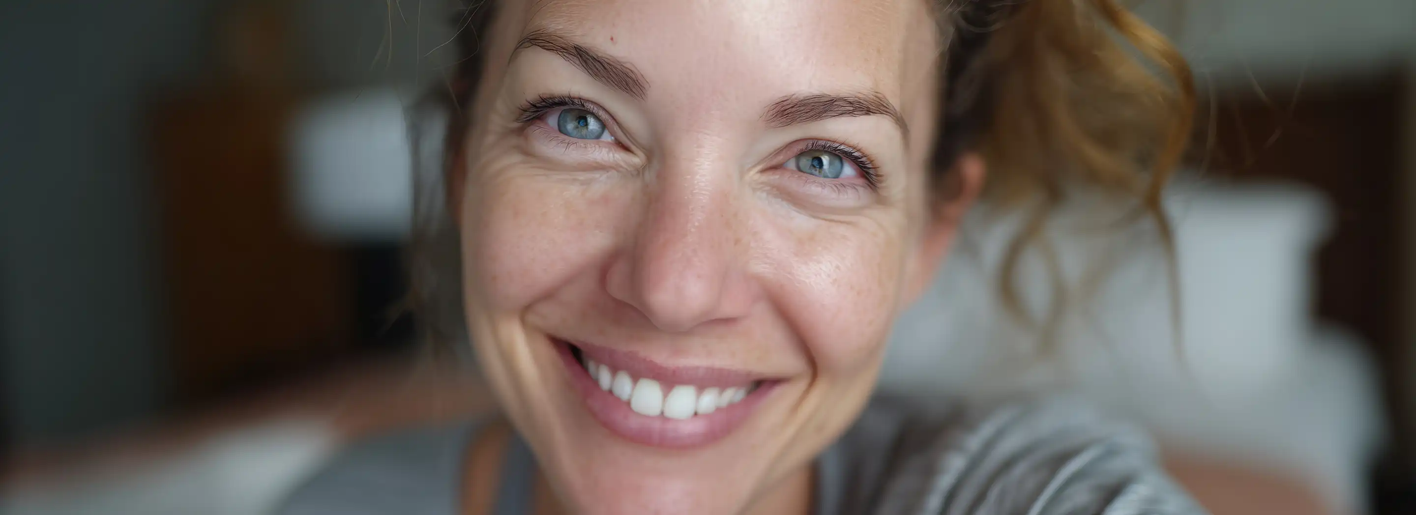 Osoba dotykająca twarzy w domowym wnętrzu, ilustrująca problemy z cerą po 30. roku życia i codzienną pielęgnację sk&oacute;ry