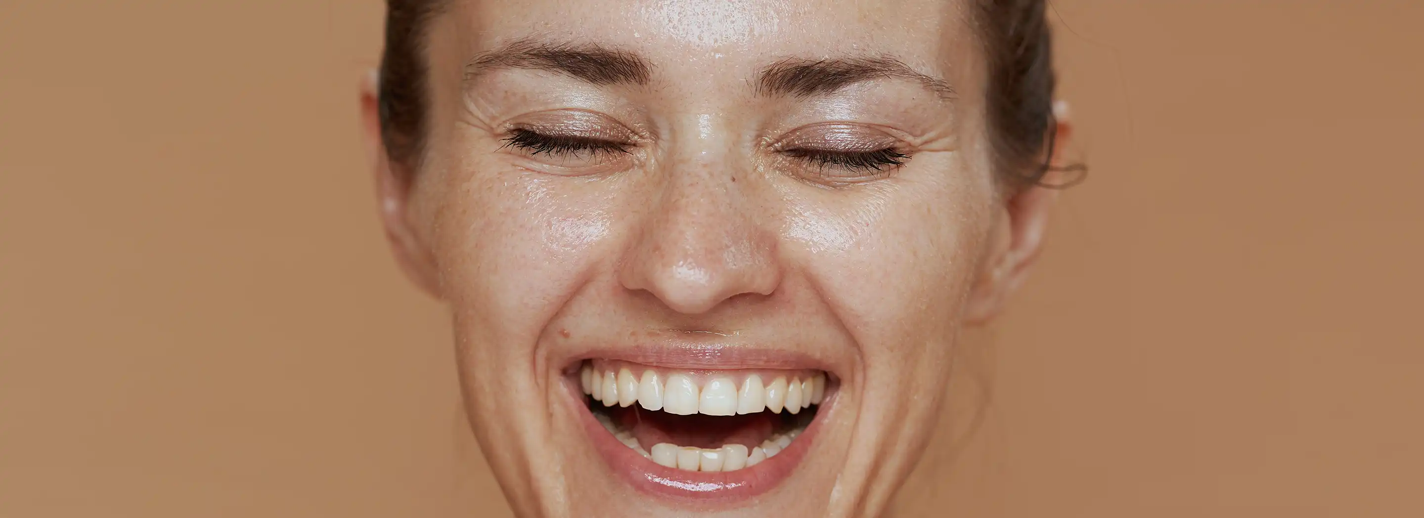 Osoba opierająca dłonie pod brodą na neutralnym tle, ilustrująca problemy ze sk&oacute;rą po 40. roku życia i zmiany kondycji cery.