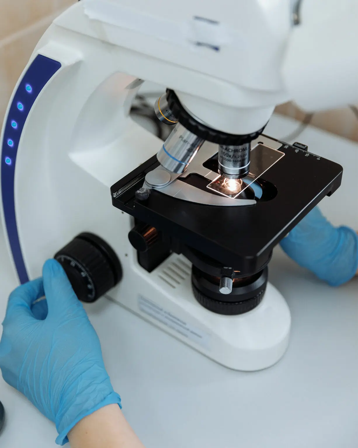 Mikroskop laboratoryjny z próbą na stole.